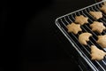 Corner of a baking grid with freshly baked gingerbread cookies for Christmas on a black background with large copy space