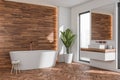 Bathtub and floating vanity in bathroom with wood look tiles. Corner view