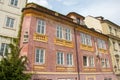 Corner of beautiful old red pink house with a bust statue and spring green bush and ivy on wall. Czech Republic Royalty Free Stock Photo