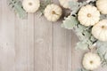 Corner border of white pumpkins and silver leaves over gray wood