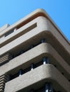 Corner of a brutalist concrete concrete tower block with textured rounded corners against a blue sky