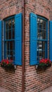 Corner building facade with bright blue shutters and red flowers in window boxes Royalty Free Stock Photo