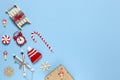 Corner creative Christmas composition. Candy cane, gift in craft paper, sled with deer, hat, alarm clock, ski, clothespins, wooden