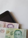 corner of an electronic tablet and Singaporean money on the table