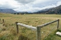 Corner fence strainers and farmland leading to mountains under cloudy sky Royalty Free Stock Photo