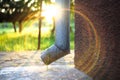 Corner of house with drain pipe with a beautiful sunset sun and rays on the background of the spring garden Royalty Free Stock Photo