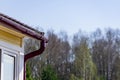 Corner of the house with gutter on a background of blue sky and forest Royalty Free Stock Photo