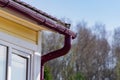 Corner of the house with gutter on a background of blue sky and spring forest Royalty Free Stock Photo