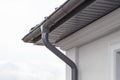 Corner of the house with new gray metal tile roof and rain gutter. Metallic Guttering System, Guttering & Drainage Pipe Exterior Royalty Free Stock Photo