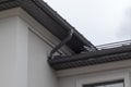 Corner of house with new gray metal tile roof and rain gutter. Metallic Guttering System, Guttering and Drainage Pipe Exterior Royalty Free Stock Photo