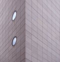 Corner of a large modern commercial building with grey rectangular cladding and round windows