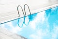 Corner of large swimming pool with stainless steel handrail staircase, clean water, marble edge and linear drains, luxury hotel Royalty Free Stock Photo