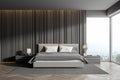 Corner of master bedroom with grey wooden walls panoramic window with countryside view comfortable king size bed standing on