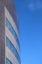 The corner of a modern curved office building against a blue sky