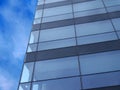Corner of a modern glass office building next to a blue sky with white clouds Royalty Free Stock Photo