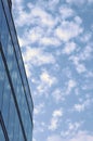 Corner of a modern glass office building next to a blue sky with white clouds Royalty Free Stock Photo