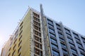 Corner of a multi-storey building under construction and a construction elevator rail outside the building to lift workers Royalty Free Stock Photo