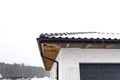 The corner of the roof of a single-family house is covered with snow. Visible the ridge, roof trusses and falling snow. Royalty Free Stock Photo