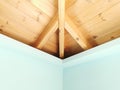 Corner of room with light blue turquoise painted plaster walls and wooden ceiling with beams. Wooden mansard Royalty Free Stock Photo