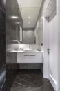 Corner with sink and mirror in luxurious small bathroom with marble walls and floor. Bathroom interior