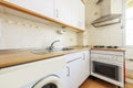 Corner small kitchen with white cabinets with wood-colored countertops and built-in white and stainless steel appliances