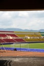 A corner of a soccer field with lush green grass, colorful spectator seats, and a backdrop of green hills