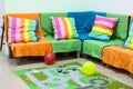 Corner sofa with colorful striped pillows, balloons on floor in the room