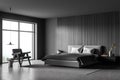 Corner view of grey bed, dark grey and wood-panel wall of bedroom