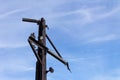 Corner view of rusted metal pole and outriggers against a blue sky