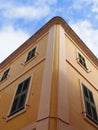 Corner view of a typical menorcan spanish house painted yellow looking upwards with a blue summer sky and white clouds