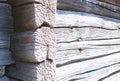 A corner and wall of an old, gray, wooden barn close-up. Corner of a wooden peasant house..