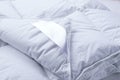 A corner of a white duvet blanket close-up. Close up Blanket against a white background. Royalty Free Stock Photo