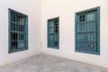 Corner wall with grunge windows with wooden green shutters and wrought iron bars and marble floor Royalty Free Stock Photo
