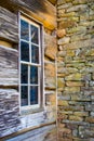 Corner window on an old log cabin next to the chimney stones