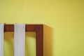 Corner of wooden chair on yellow background sunlight from window on the wall Royalty Free Stock Photo