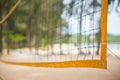 Corner of yellow voleyball net on beach among palm trees