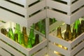 Corners of shelves made from white painted wood crates with transparent glass bottles inside. Retro style beer bottle rows. Royalty Free Stock Photo