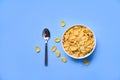 Cornflakes in bowl on blue background spoon for cereal healthy food Royalty Free Stock Photo