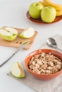Cornflakes in bowl with fresh apples cut in pieces, bananas, wooden board
