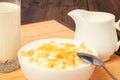 Cornflakes in bowl and glass of milk on wooden table Royalty Free Stock Photo
