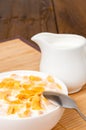 Cornflakes in bowl, milk jug and napkin on wooden table Royalty Free Stock Photo