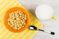 Cornflakes in bowl, spoon on napkin, milk, spoon on table