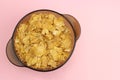 Cornflakes in a glass plate on a pink background