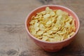 Cornflakes in a pink bowl, on a wooden table. copy space