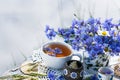 Cornflower herbal tea in white cup on white crochet napkin on wooden table, healthy cornflower drink with honey