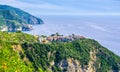 Corniglia traditional typical Italian village with colorful buildings on rock cliff and Manarola, Genoa Gulf, Ligurian Sea, blue s