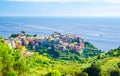 Corniglia traditional typical Italian village with colorful multicolored buildings houses on rock cliff and boat on water of Genoa