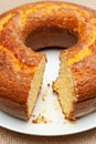 Cornmeal Cake Bolo de Fuba cut Brazilian style on a white plate. Isolated on jute. Front view. Close-up. Vertical shot
