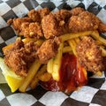 Cornmeal Fried Alligator Chunks over French Fries.