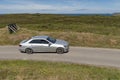 Silver saloon car driving on a country road. Cornwall England UK